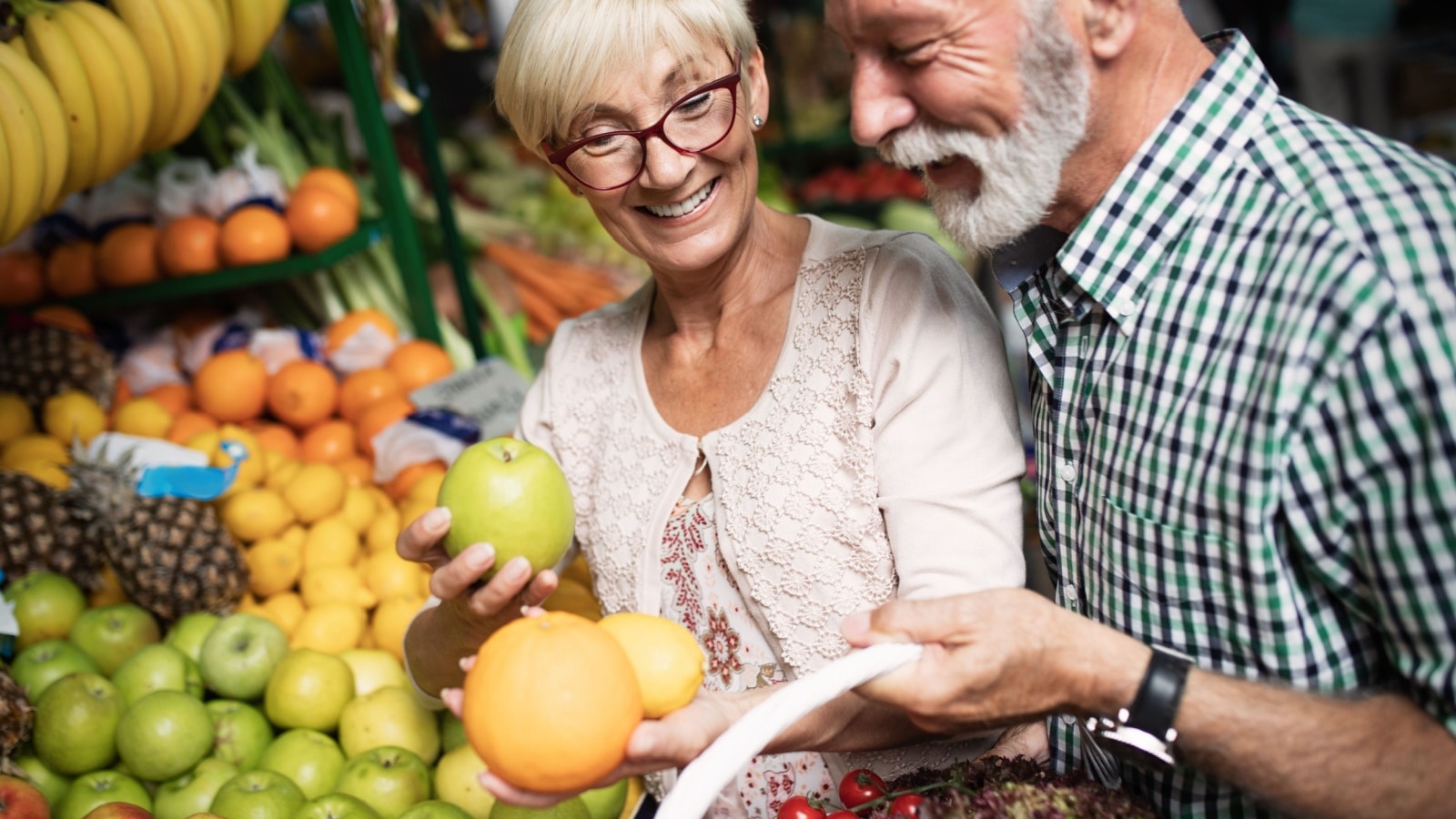 Older couple happy grocery shopping vegetable aisle.