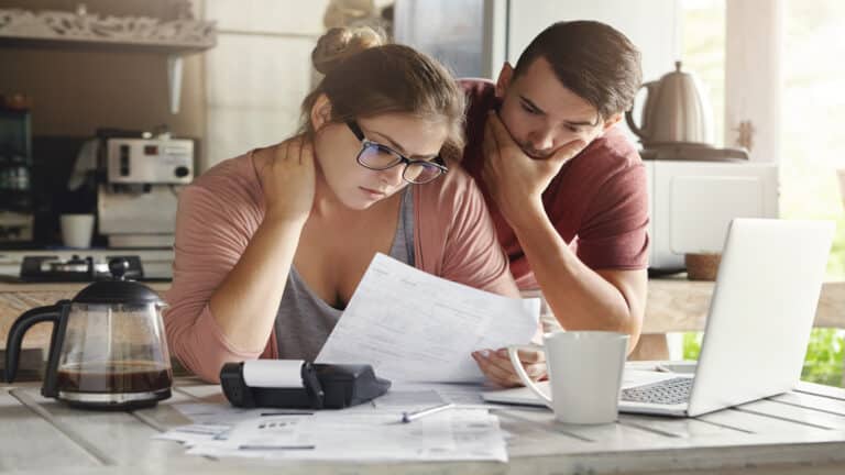 Young couple stresssed with debt money problems, not able to pay bills looking at computer.