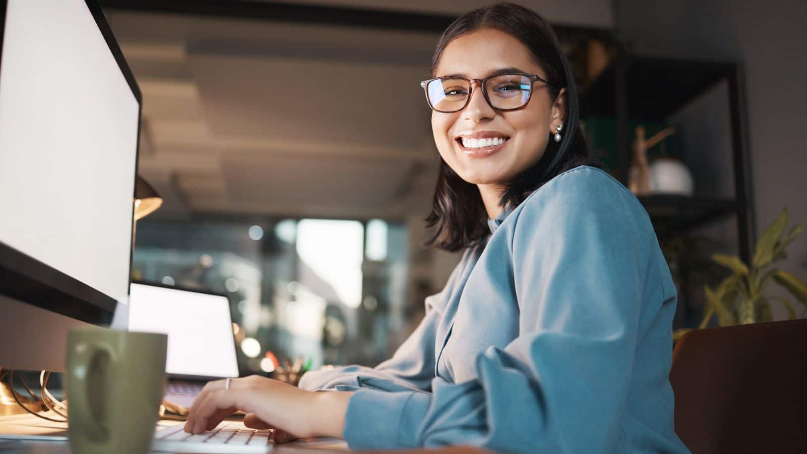 woman at computer in home office smiling.