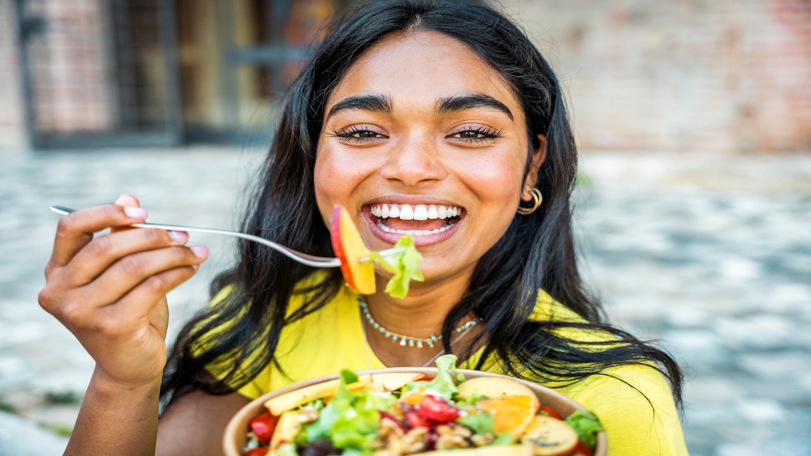 woman eating healthy fruit salad snack.