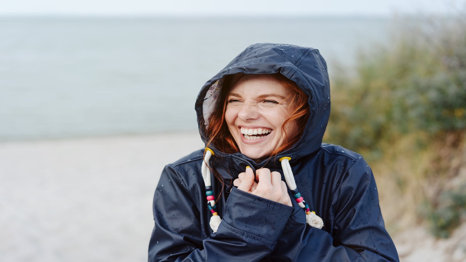 Woman embracing cold weather smiling wearing coat.