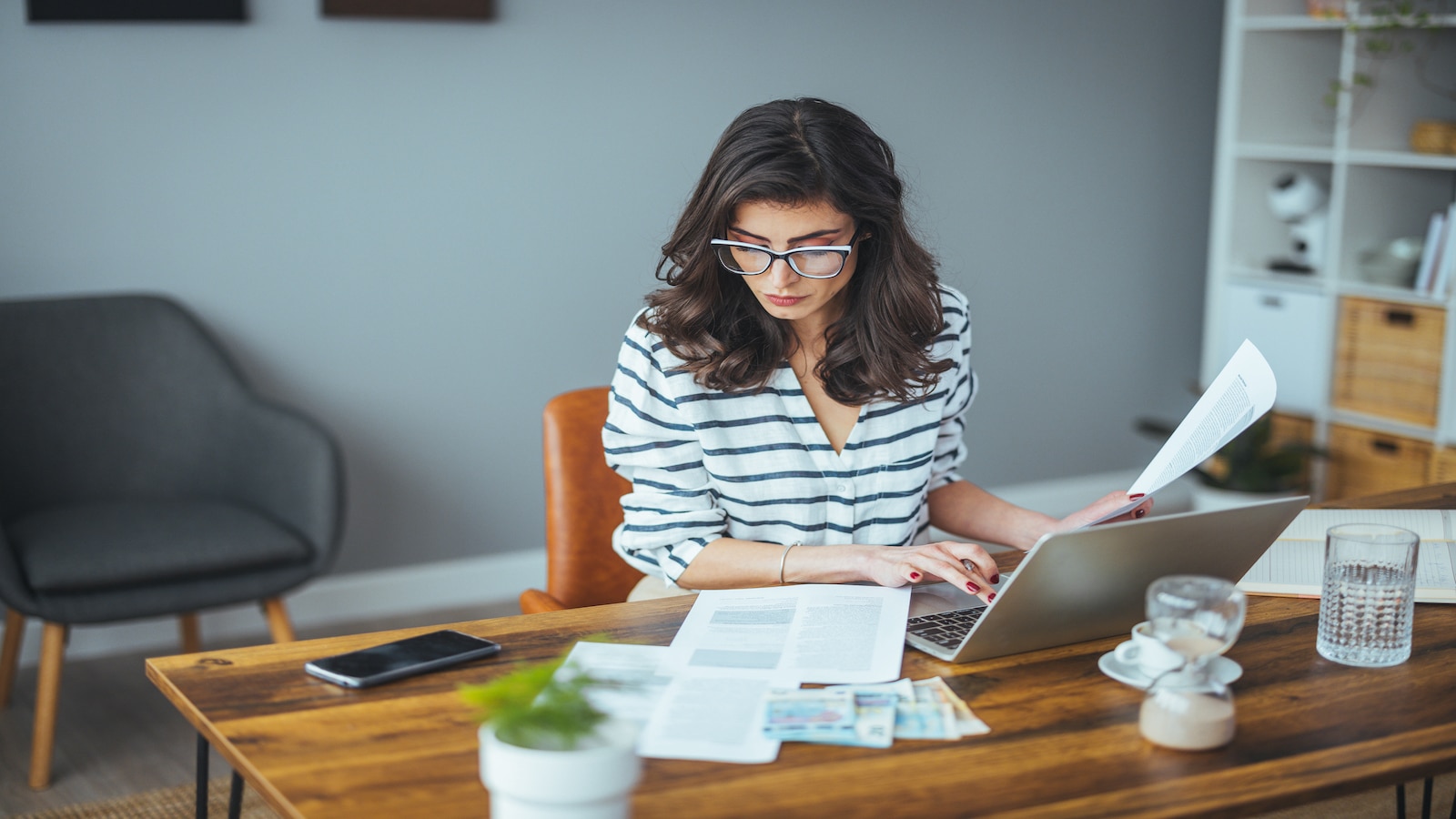 woman on computer looking through papers.