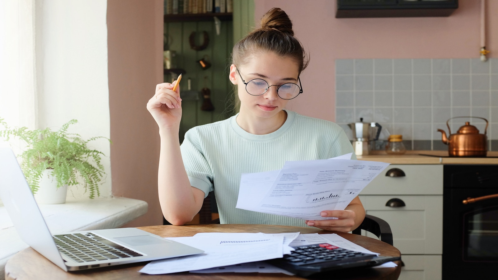 woman paying bills at kitchen table .
