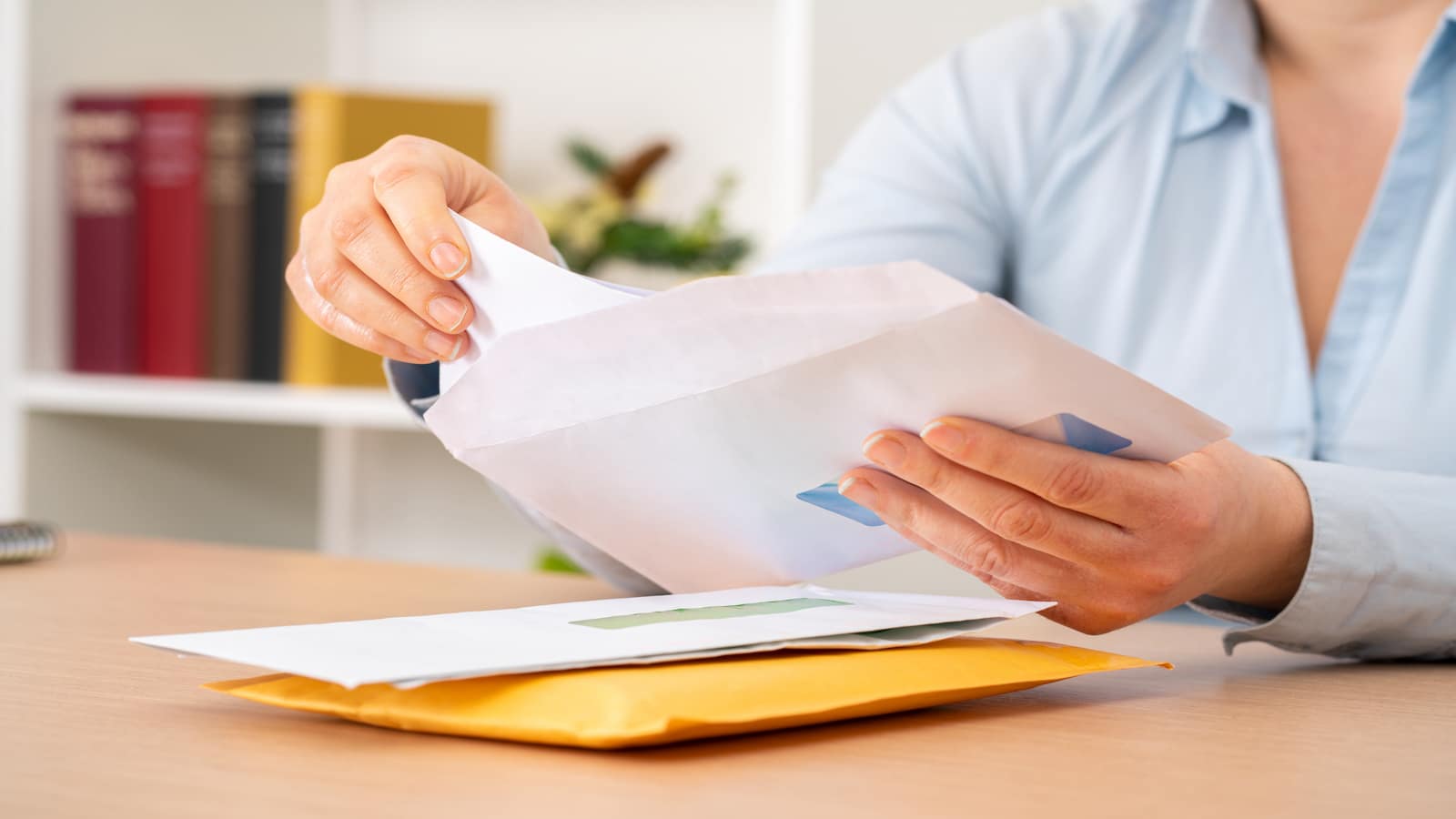 woman putting a letter inside an envelope at office.