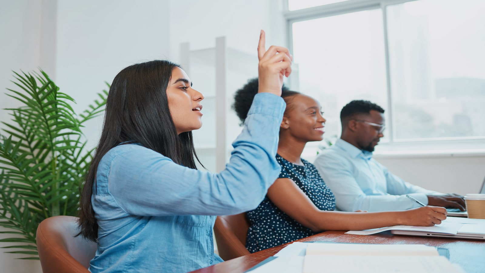 woman raising hand in meeting to ask question.