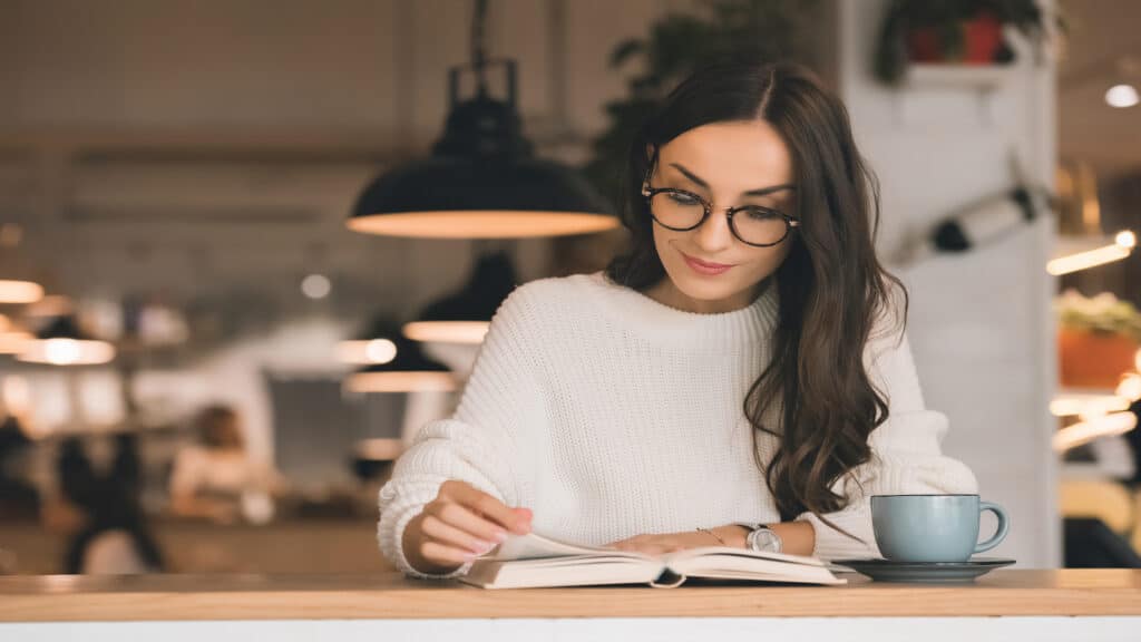 Woman reading book in cafe.