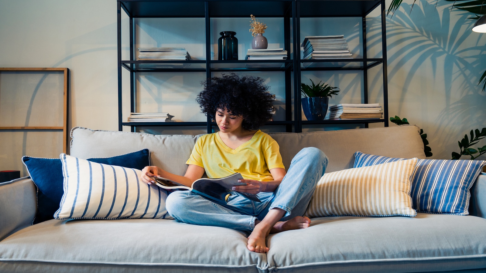 woman reading magazine on couch.