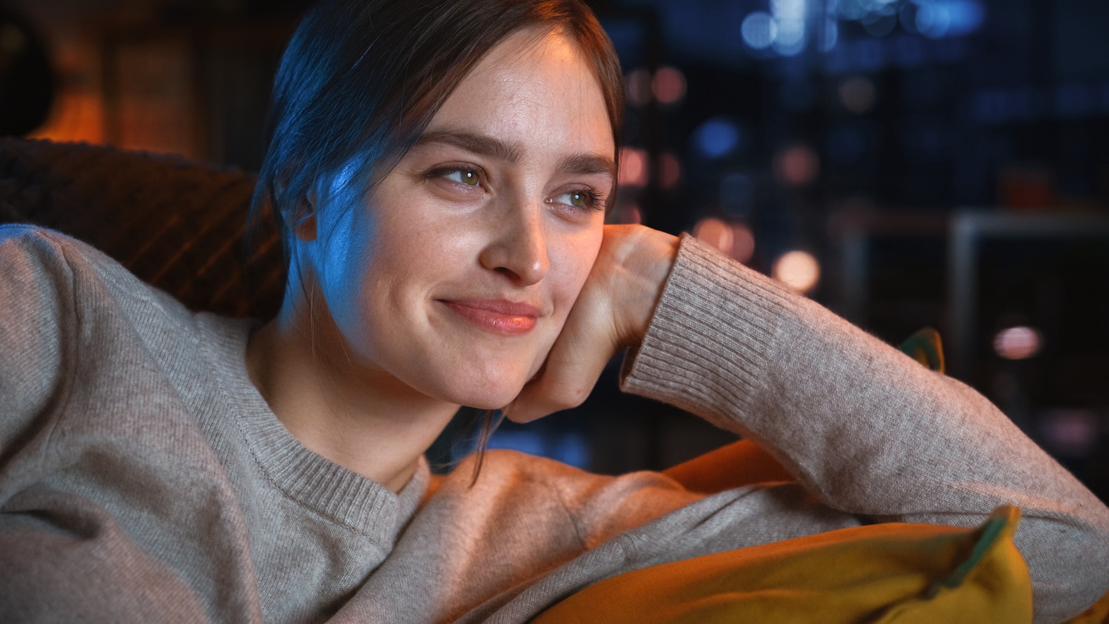 woman smiling laughing lounging on couch at night.
