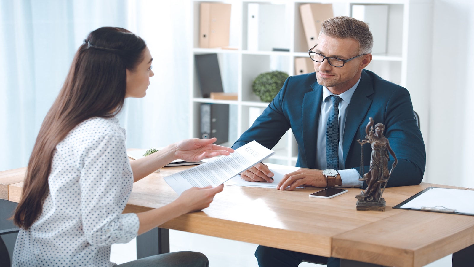 Woman talking to lawyer business man looking at papers in office.