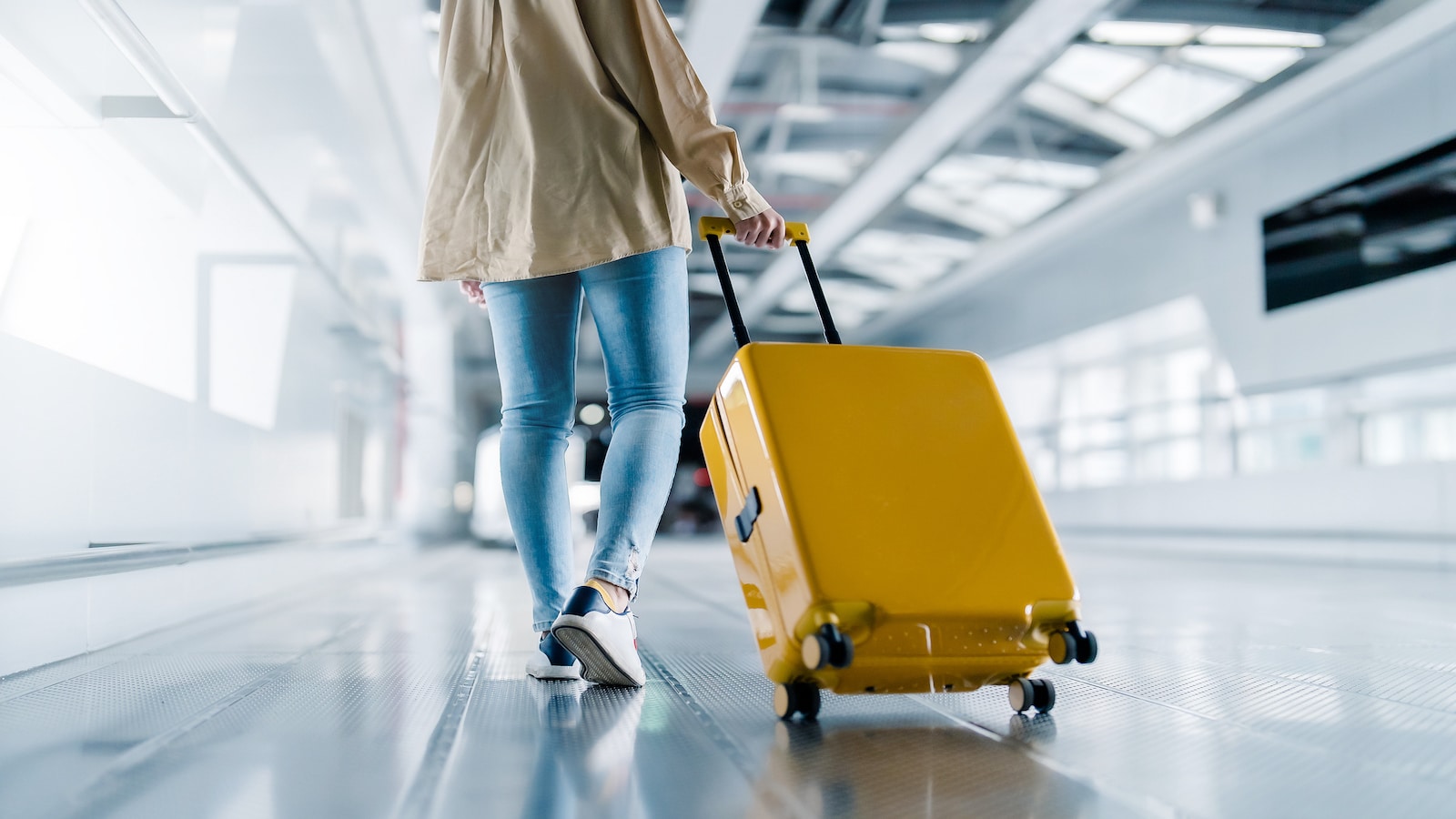 Woman walking in airport with suitcase.