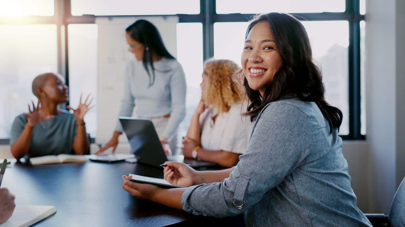 woman writing with team for meeting.