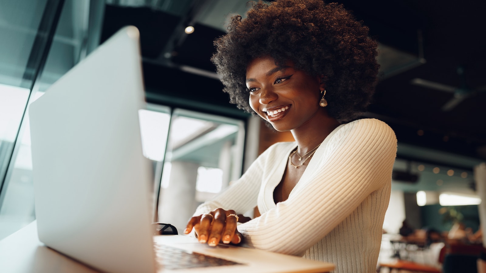 Smiling young woman sitting with laptop in cafe
