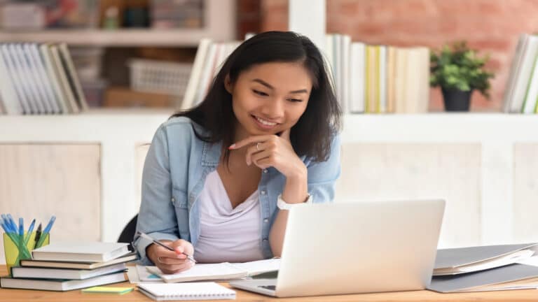 young woman studying working at desk with computer in office or library.