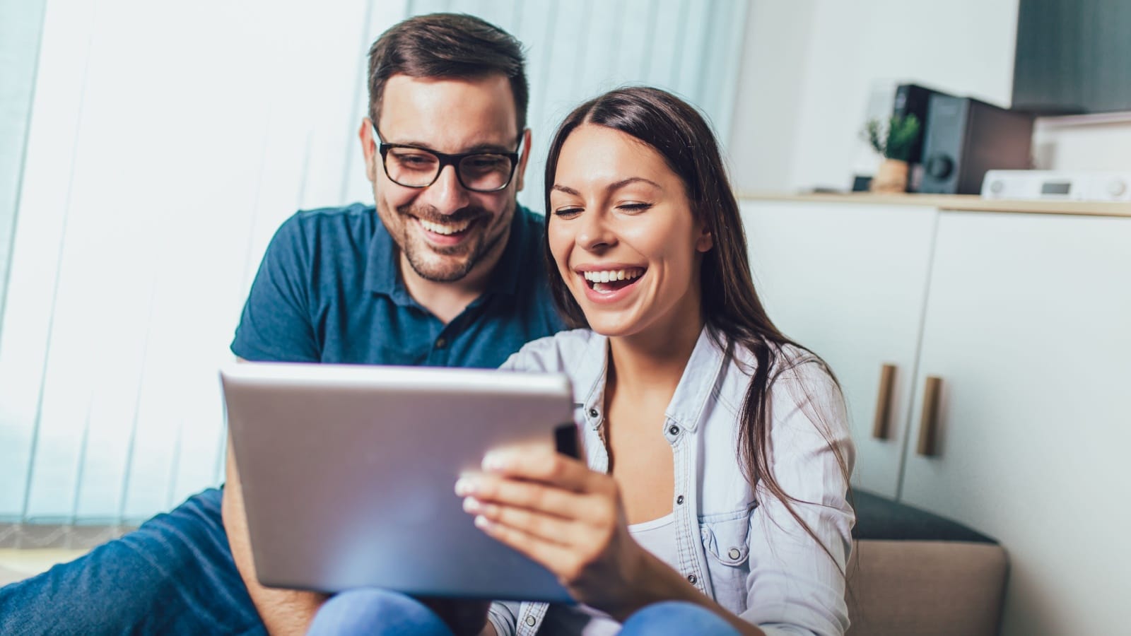 Happy young couple enjoying time online on digital tablet.