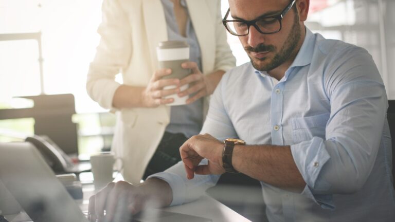 Man looking at watch at work thinking.