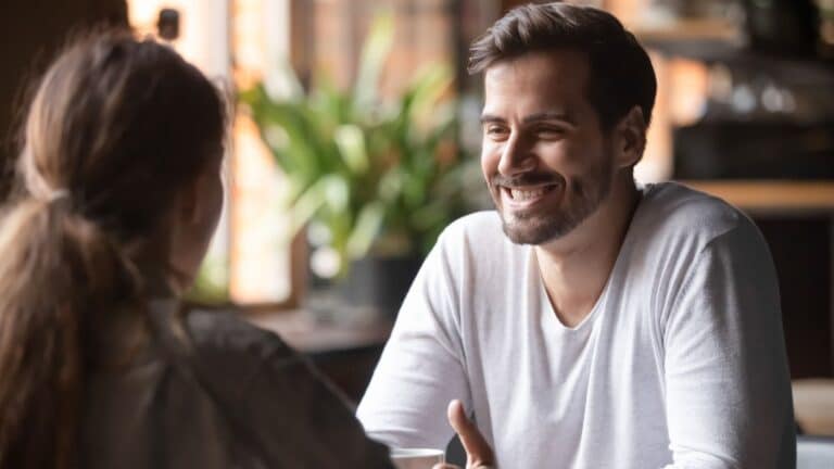 Rear view woman sitting at table in cafe with handsome smiling man.