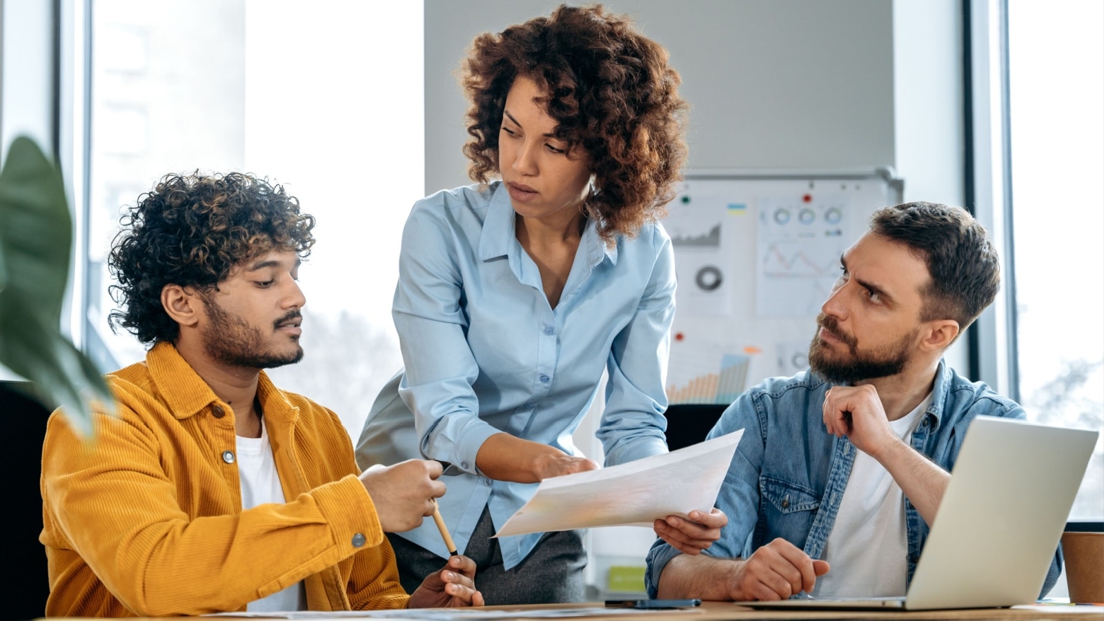 Successful people of different nationalities, creative business team, working together on a project in a modern office, watching presentation, discussing ideas, brainstorming. Teamwork, collaboration.