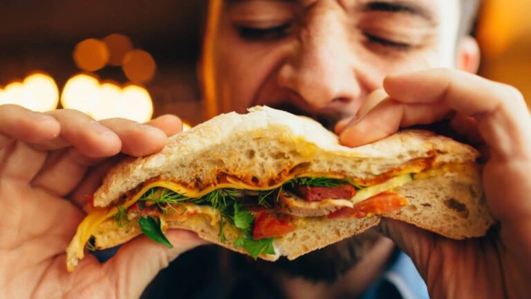 Man in a restaurant eating a hamburger, he is hungry and having a good bite. Burger dinner