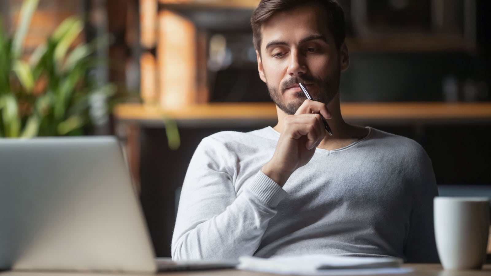 man sitting at table drink coffee work at laptop thinking of problem solution.