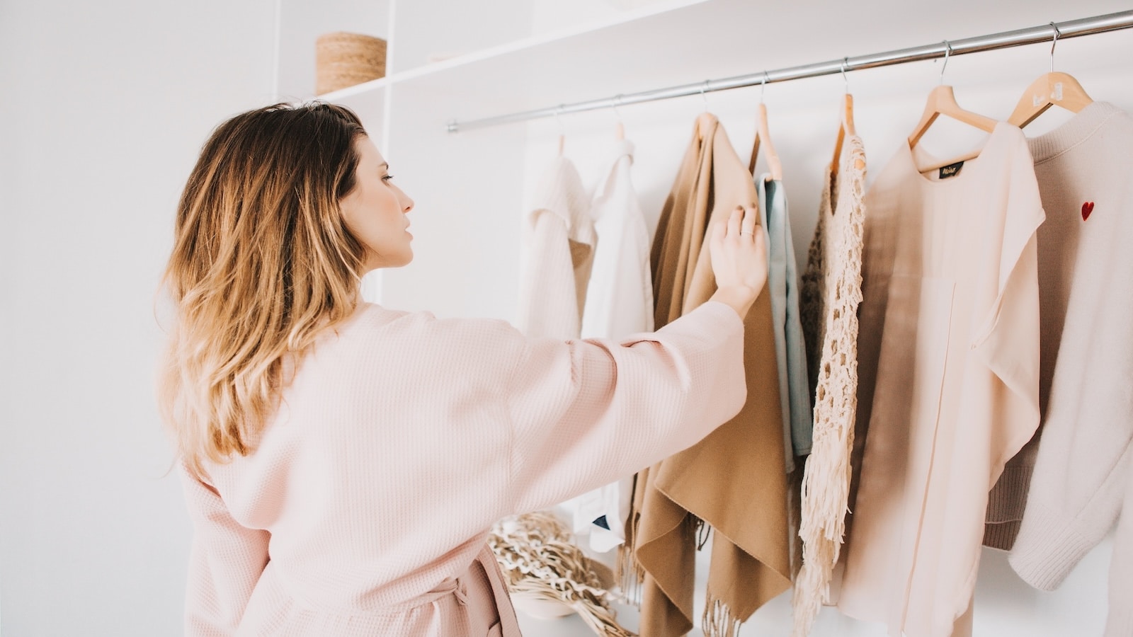 woman looking through clothes in closet changing outfit.