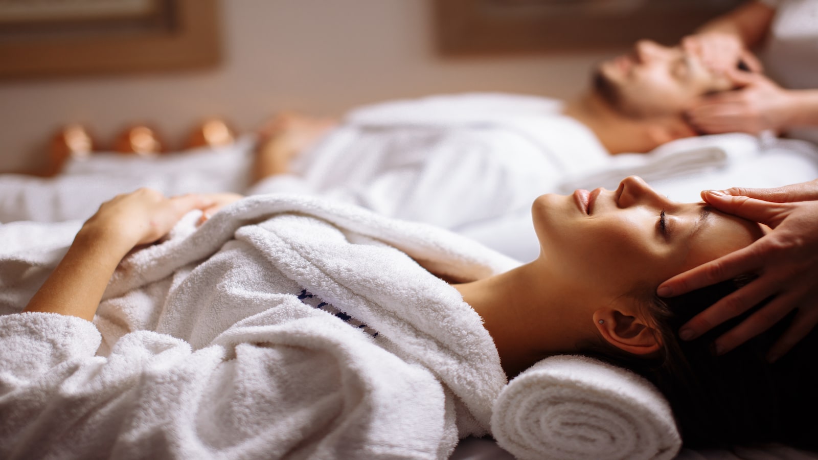 Young couple receiving head massage at beauty spa.