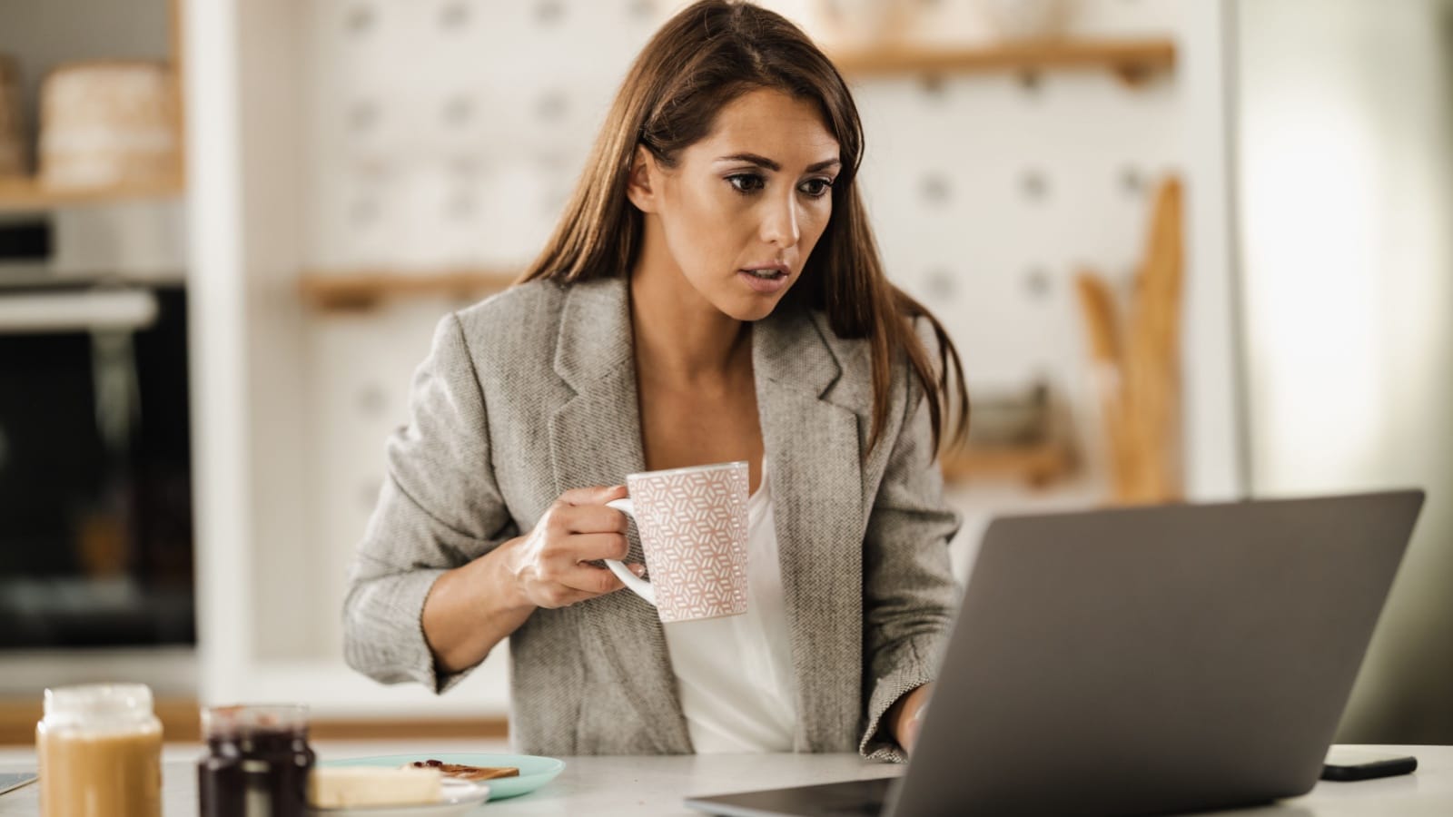 young woman multi-tasking working and eating breakfast stressed