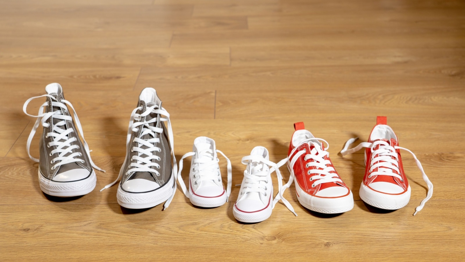 Conceptual image of gumshoes sneakers shoes of father mother and son daughter family on vintage wood floor in different sizes in Sweet home togetherness Happy Family.
