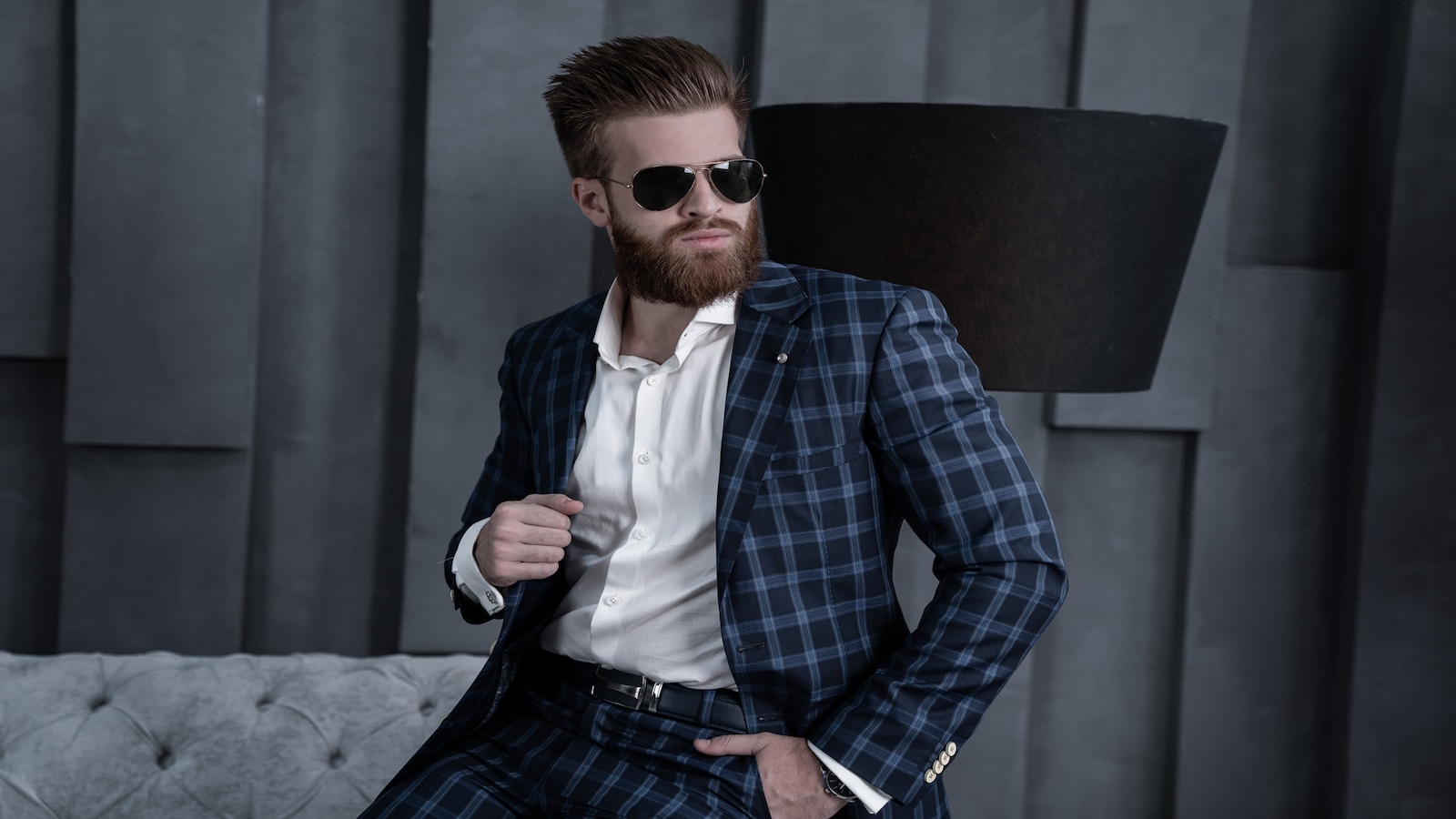 Handsome stylish man in blue suit sitting on sofa.
