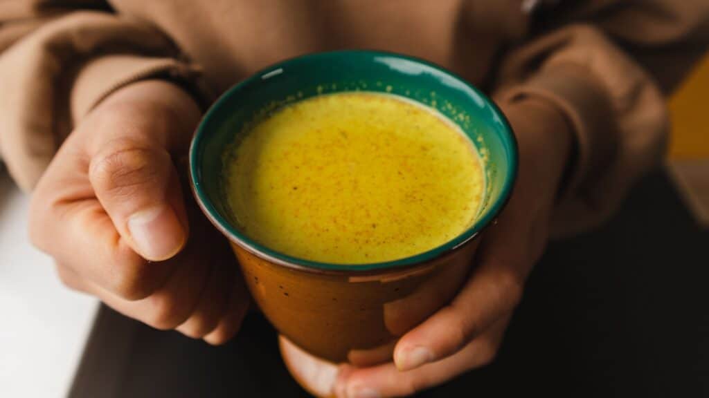 Hands holding a cup with golden milk.