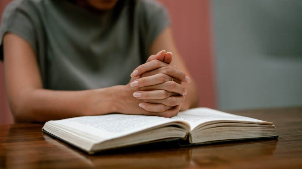 Religious concept. Belief. Close-up. A young woman praying thanks to the holy scriptures. God's teachings based on faith and faith in God, religion, belief, hope, love, prayer.