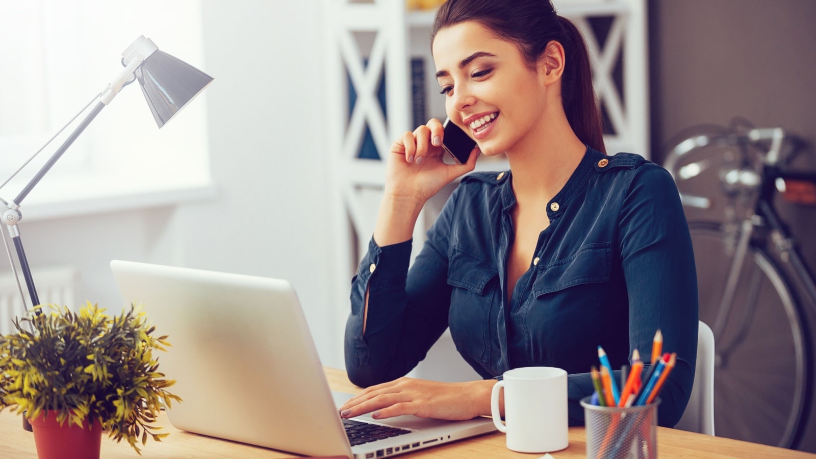Smiling woman talking on the phone and smiling while sitting in office.