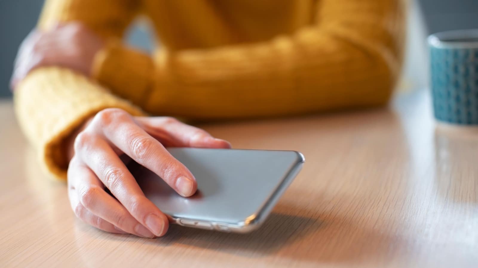 Woman Concerned About Excessive Use Of Social Media Laying Mobile Phone Down On Table.