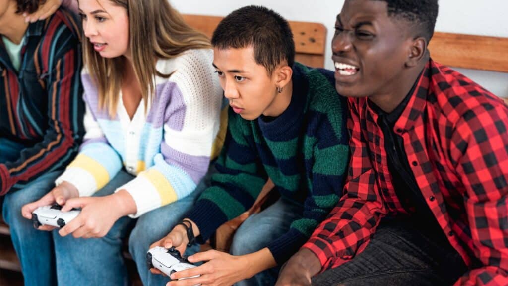 Young multiracial teenagers playing online video game console at home - Youth people addicted to new technology gaming entertainment.