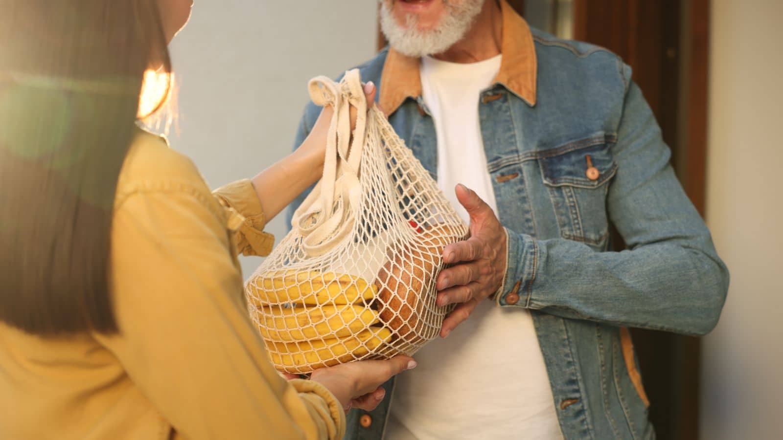 Young woman with net bag of produce helping a neighbor.