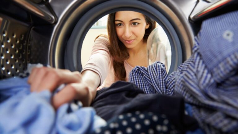 Woman Doing Laundry Reaching Inside Washing Machine