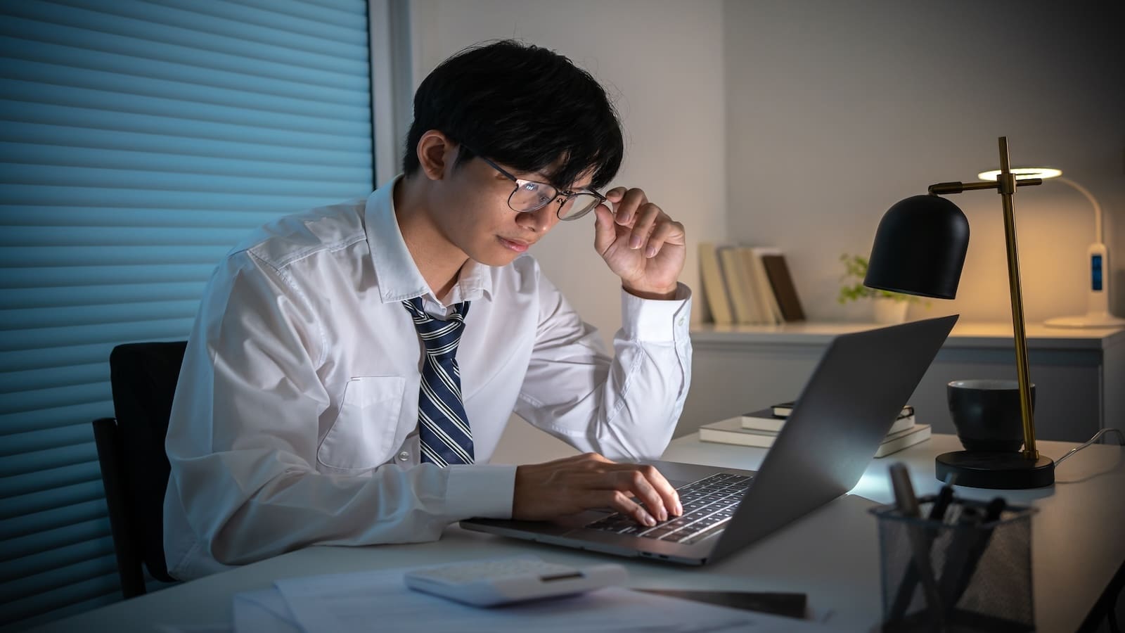 Man working on laptop in night office.