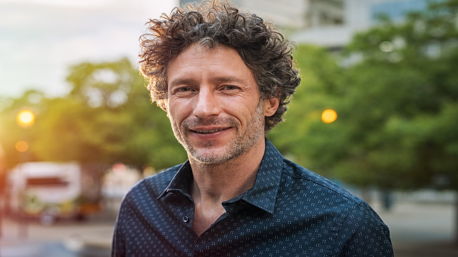 Happy smiling man in street at sunset.