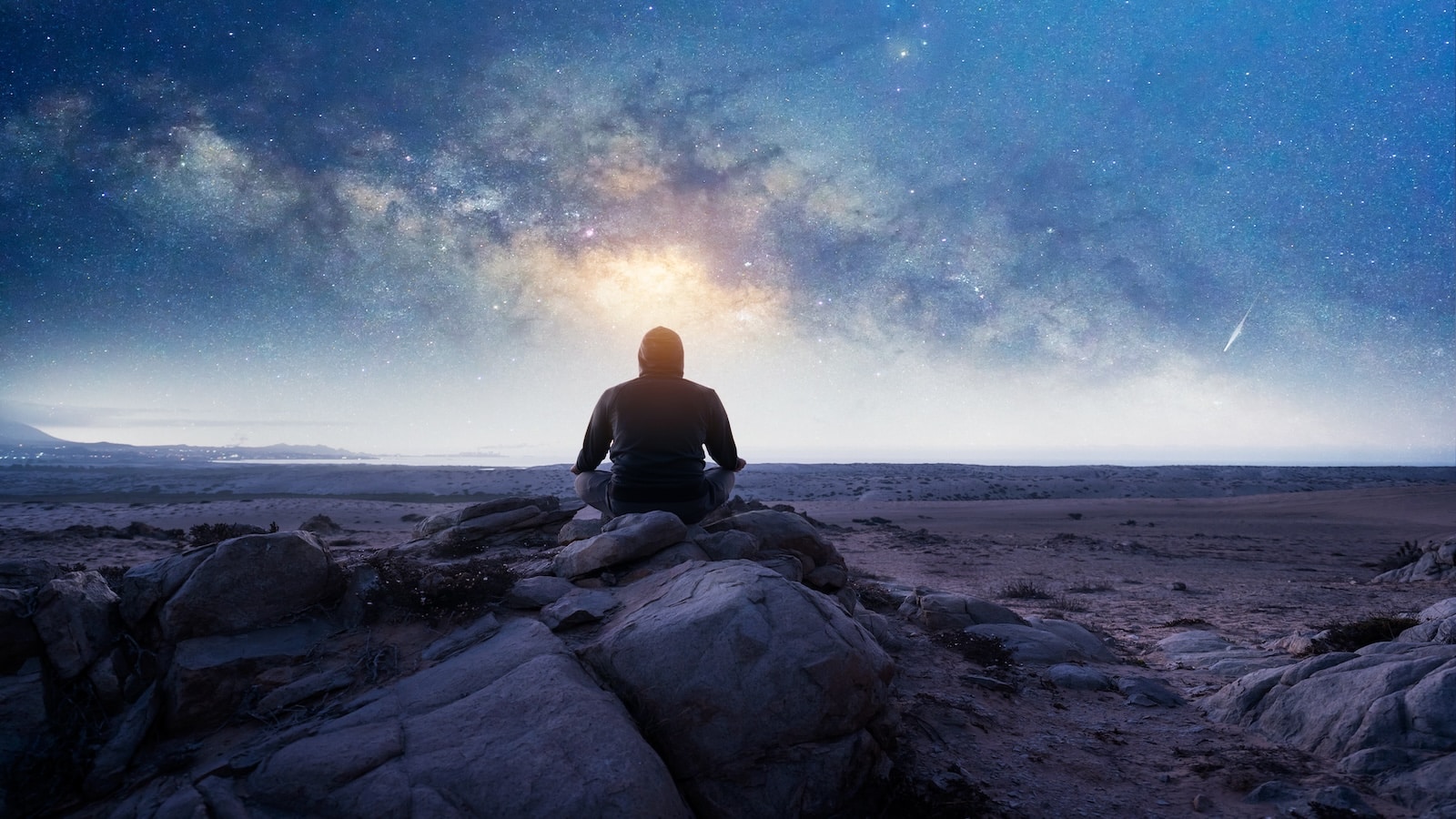 silhouette of a person sitting on the mountain meditating under the Milky Way and starry night.