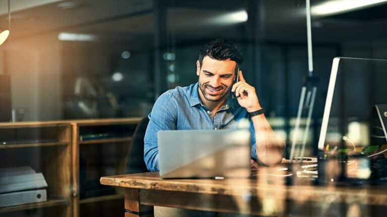 Young businessman talking on his phone and using a laptop.
