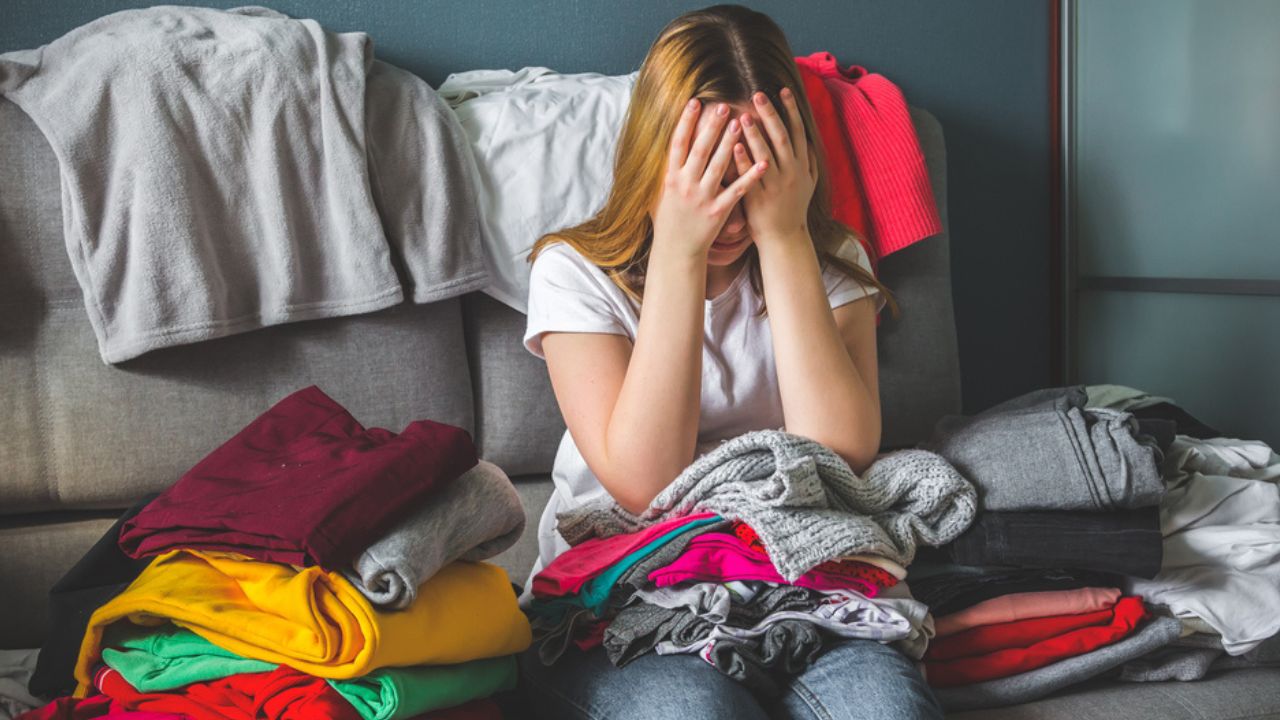Fast fashion, the girl puts things in order in the closet. A bunch of colorful clothes. The concept of processing, second hand, eco, minimalism, consumption of goods.