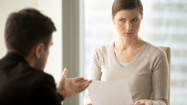Millennial businesswoman with skeptical facial expression holding contract document and listening unconvincing offer of business partner. Suspicious terms of agreement, doubtful investor, fraud, scam