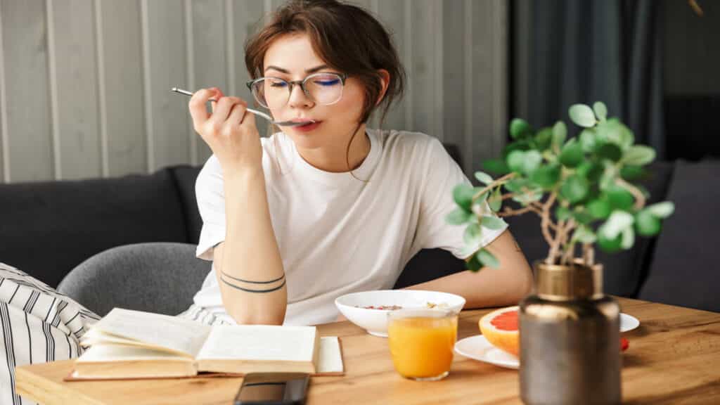 woman eating while reading a book