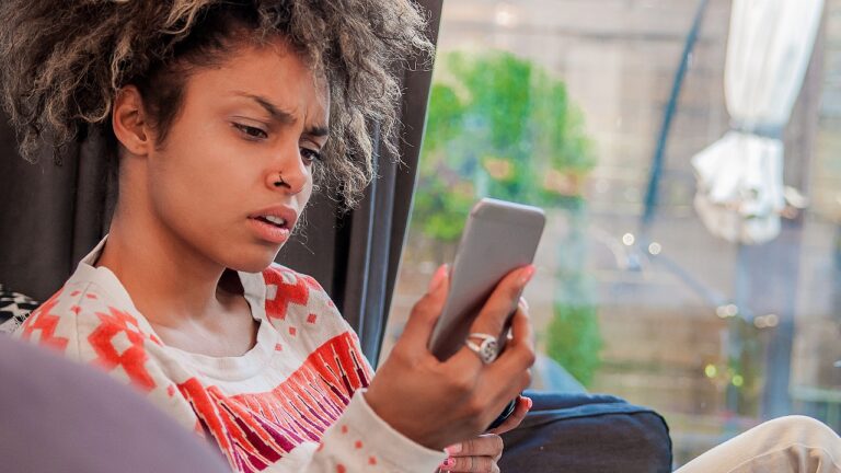 Annoyed woman looking at her cell phone, angry, disbelief