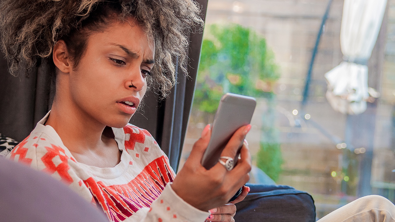 Annoyed woman looking at her cell phone, angry, disbelief
