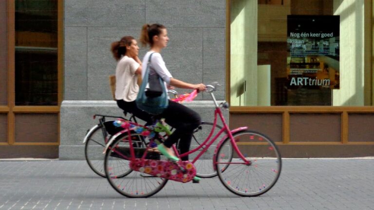 Two women riding bikes in a European city