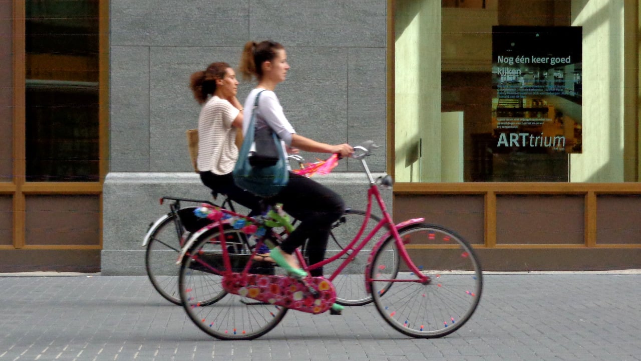 Two women riding bikes in a European city