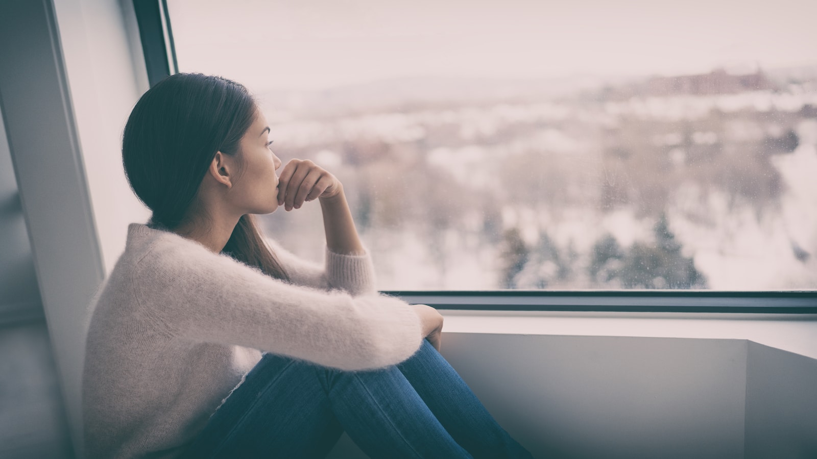 Woman staring out a window feeling sad or loneliness.