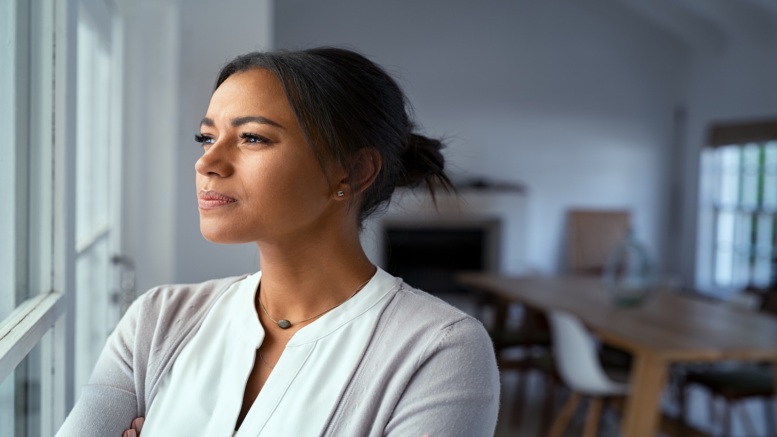 Woman looking outside window with uncertainty, deep in thought.