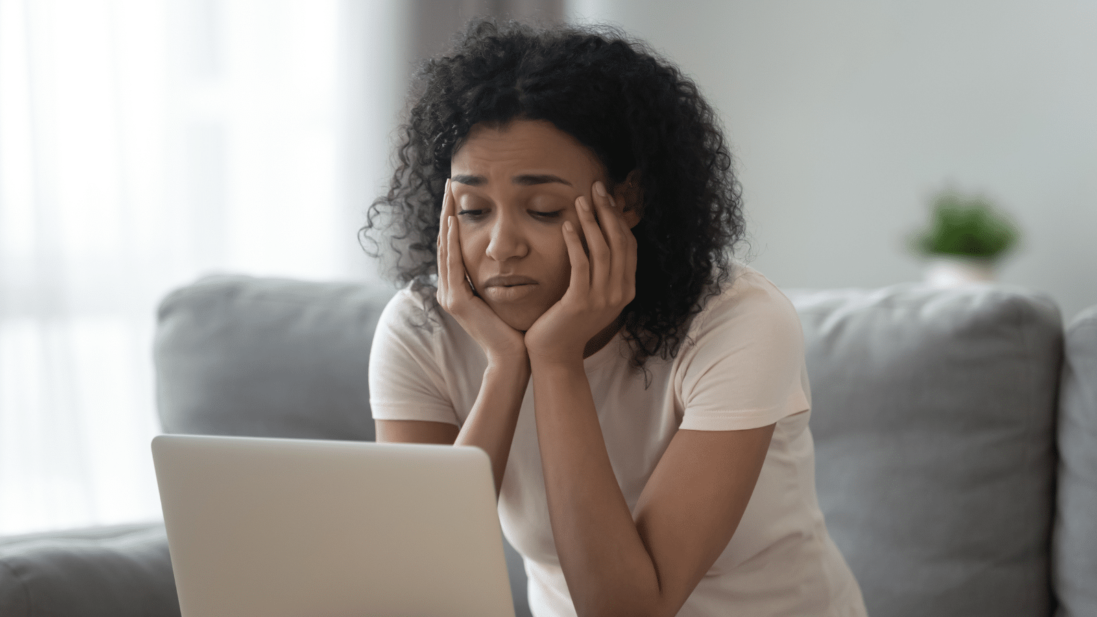 Woman procrastinating, tired of learning sitting at home looking at laptop.