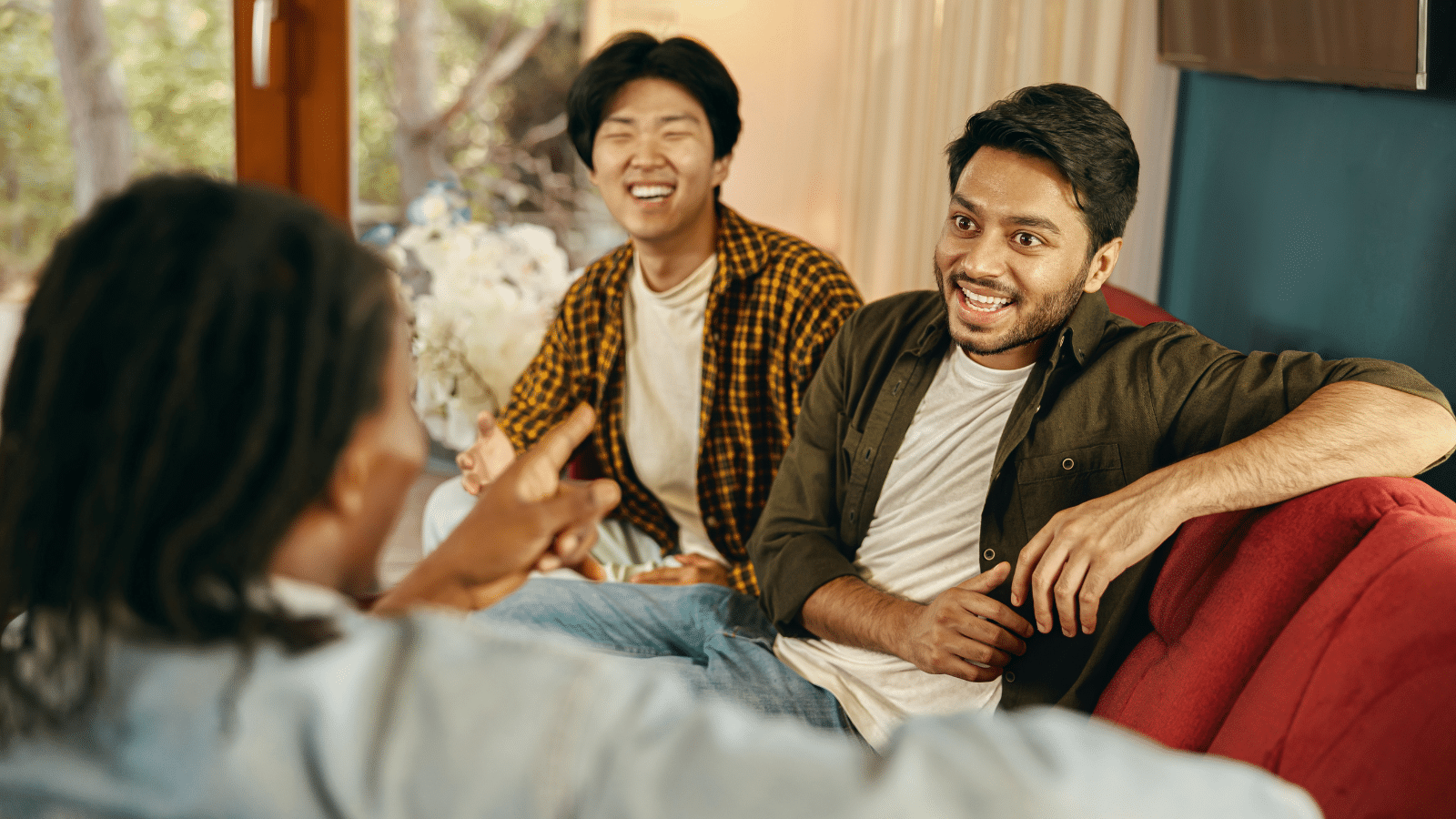 Young people talking each other while having weekend home party together looking happy.